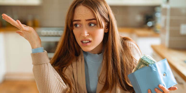 frugal american woman holding wallet looking concerned and annoyed