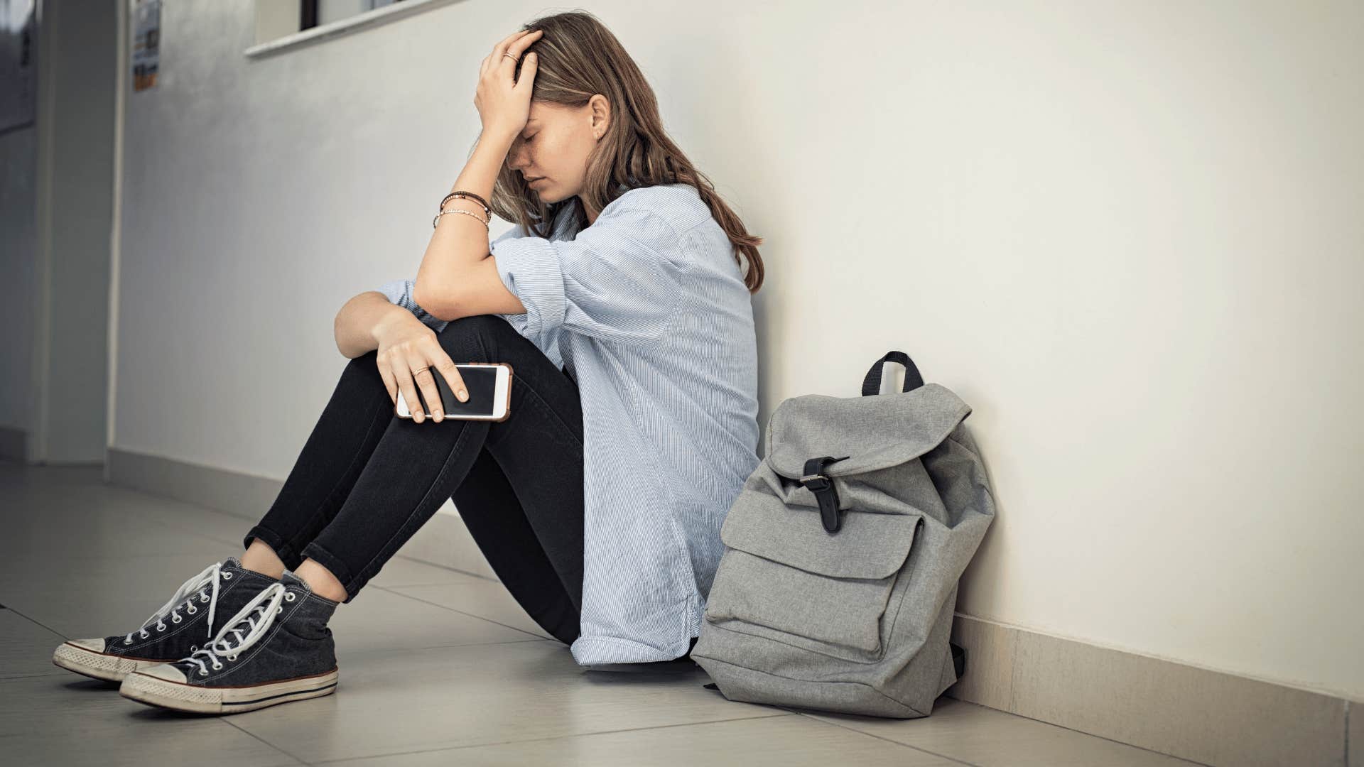 Sad teenager raised by soft parents feeling stressed in school hallway