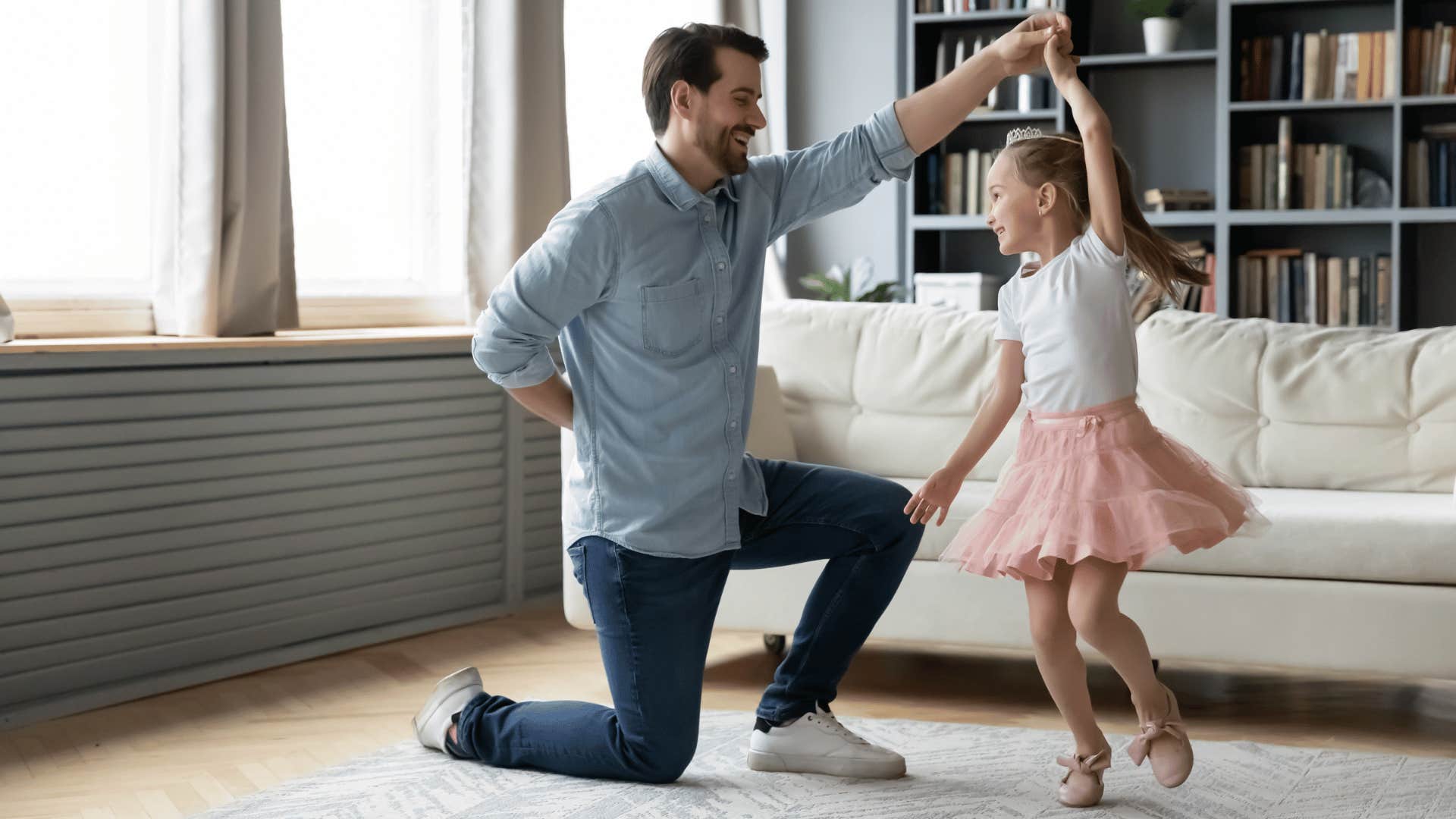 Dad who practices soft parenting dancing with his young daughter at home