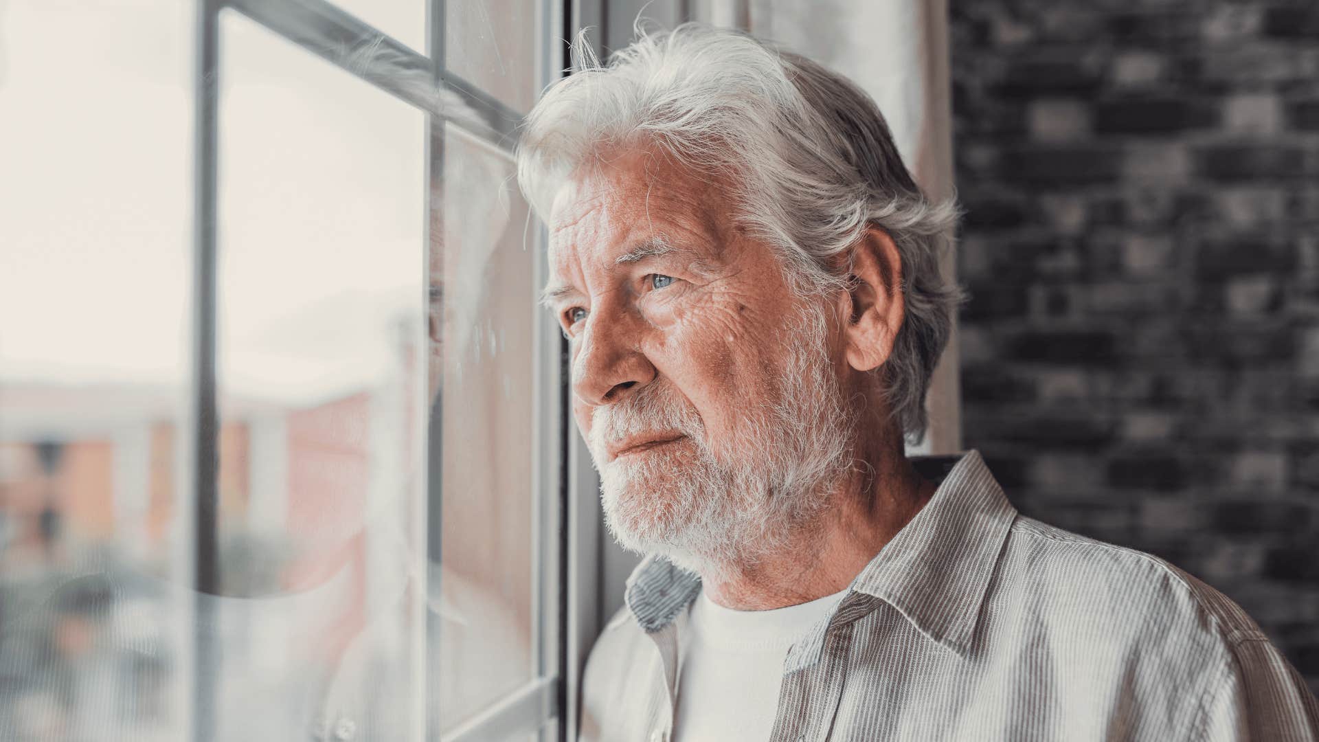 Grandfather looking sadly out the window alone 