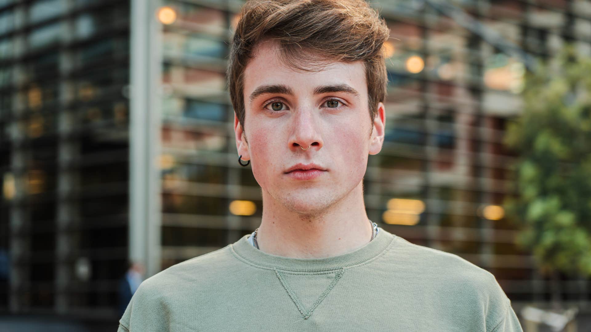 serious young man standing outside thinking