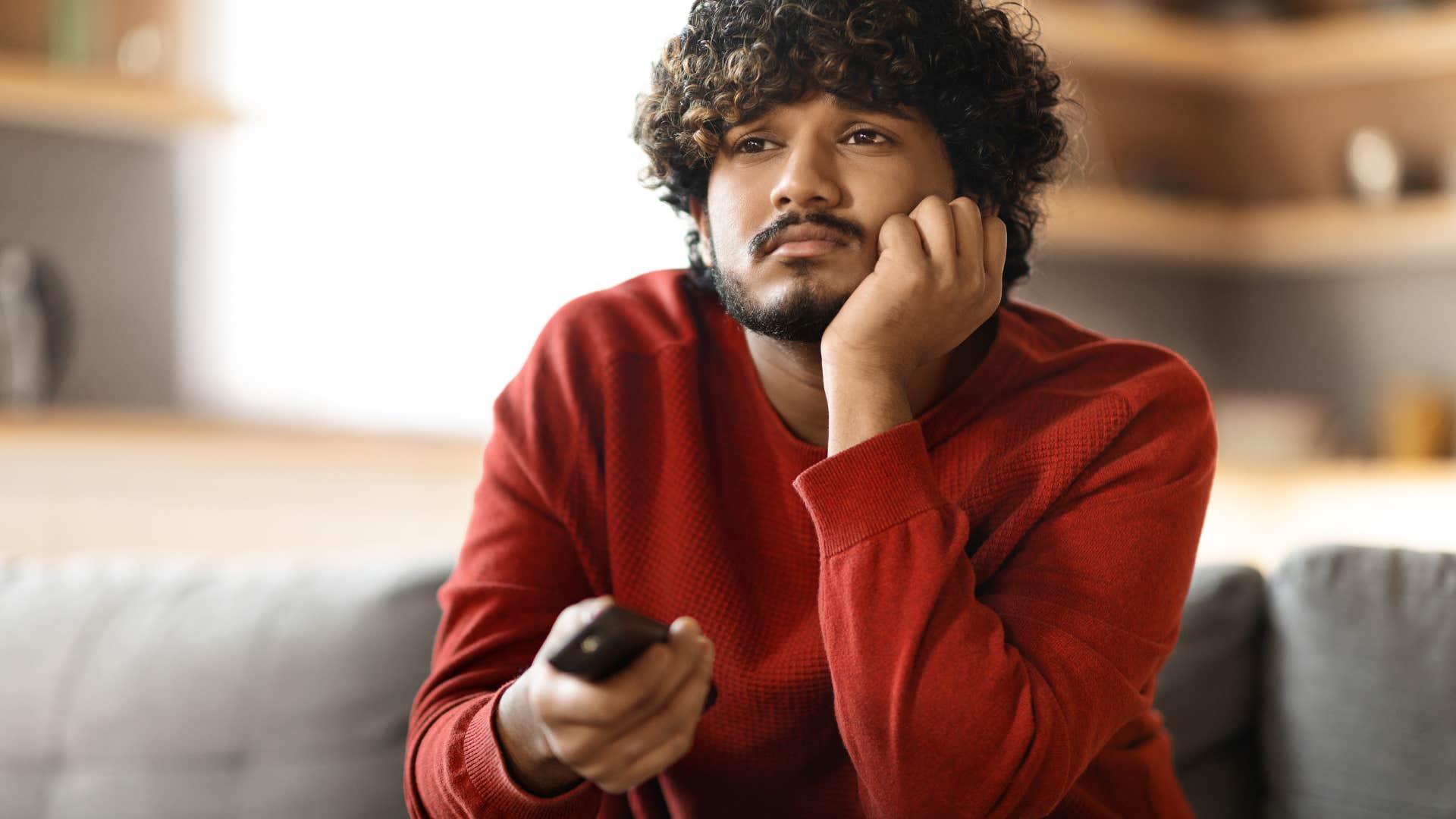 upset man watching tv thinking people don't like him or want him around