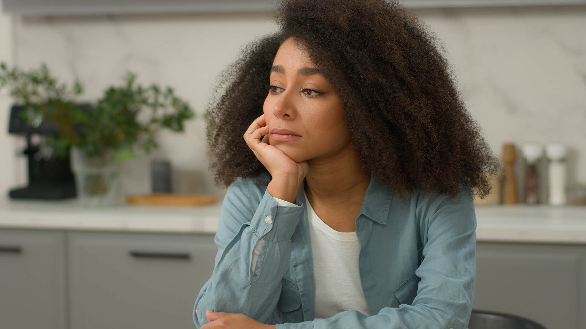sad woman sitting in kitchen deep in thought
