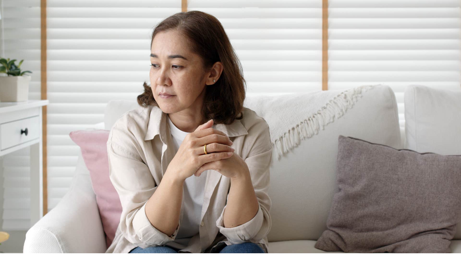 Millennial parent sitting on the couch with an annoyed expression on her face
