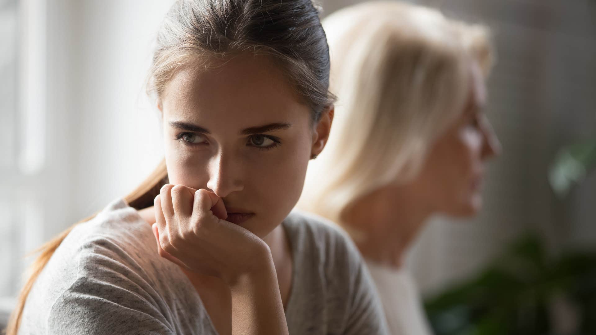 Adult daughter looking upset turned away from her toxic mother