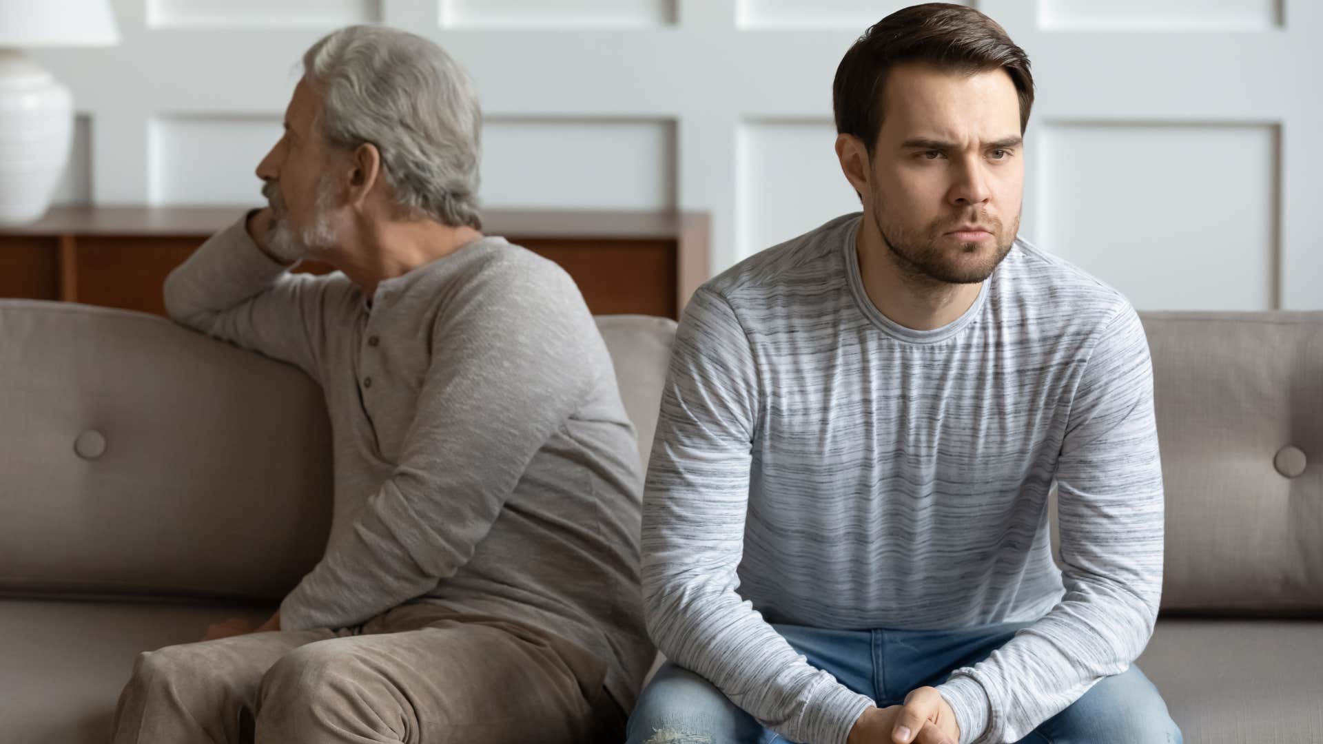Adult son angrily looking away from his toxic father 