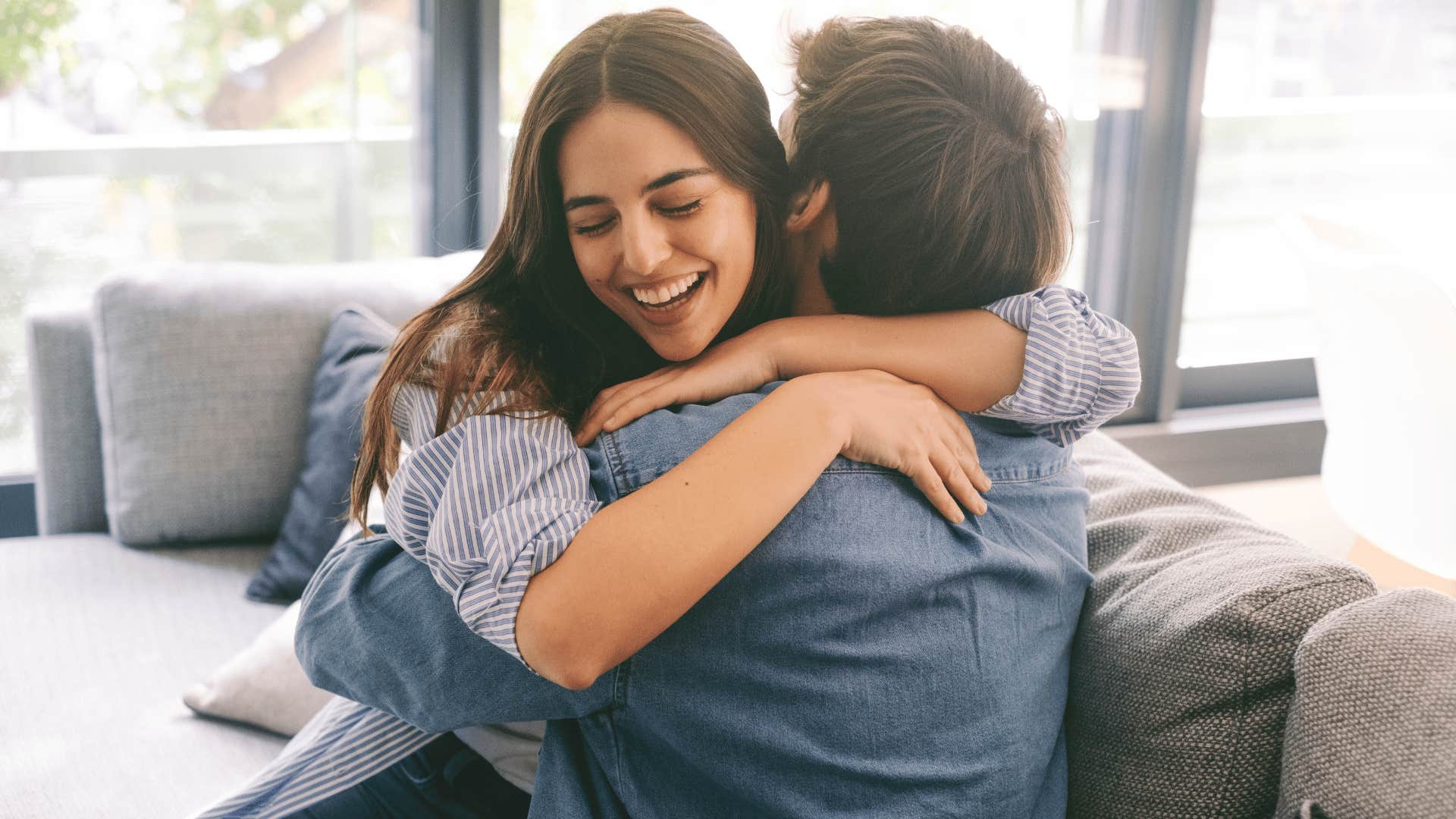 Couple hugging on a couch in a sunny room 