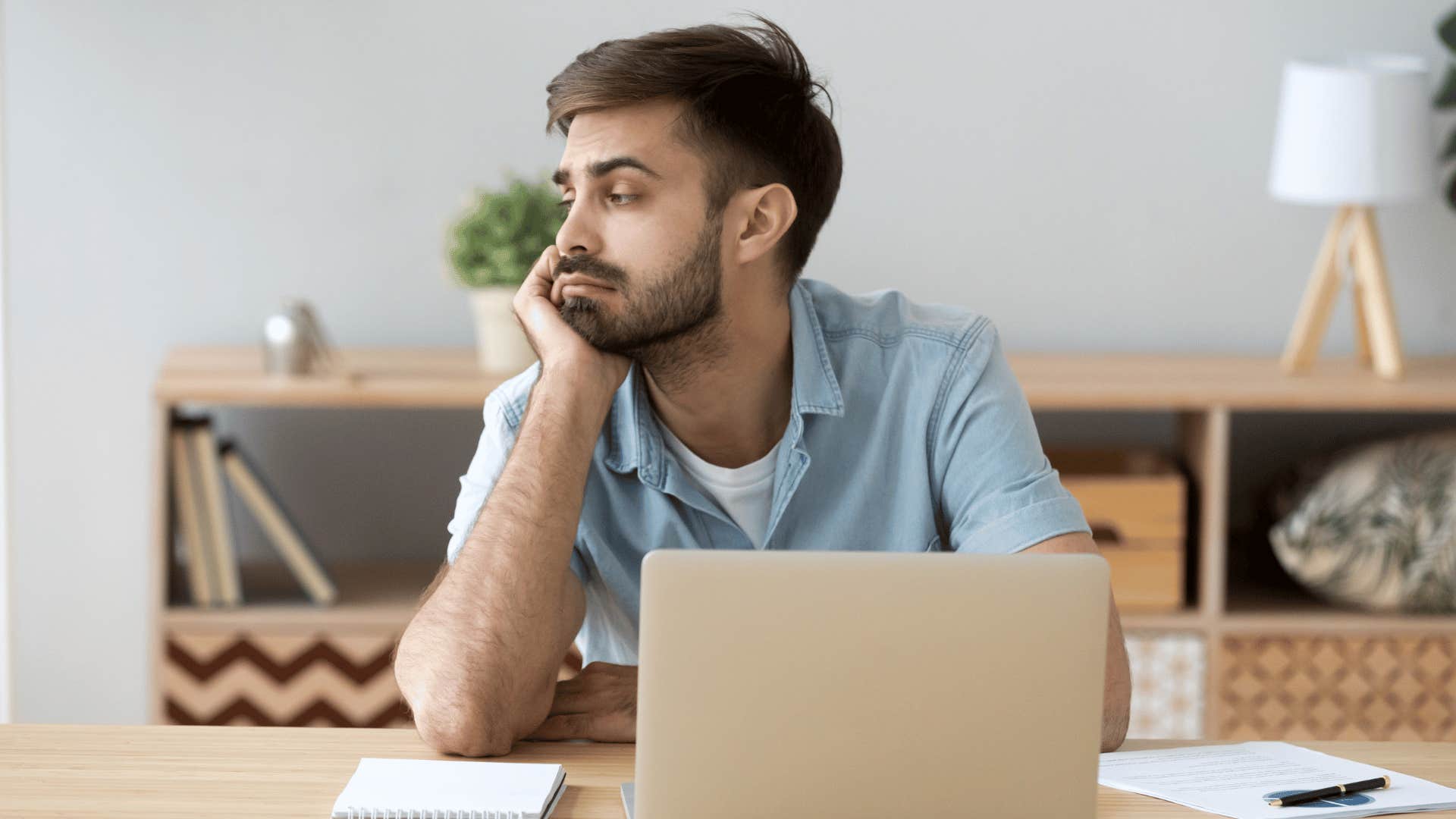 Adult son who dropped out of college looking sad at a computer