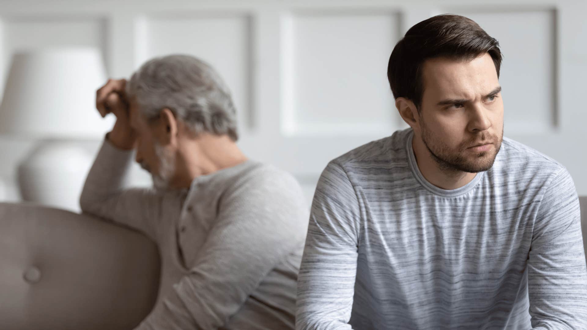 Older parent turned away from his grown son who looks angry 