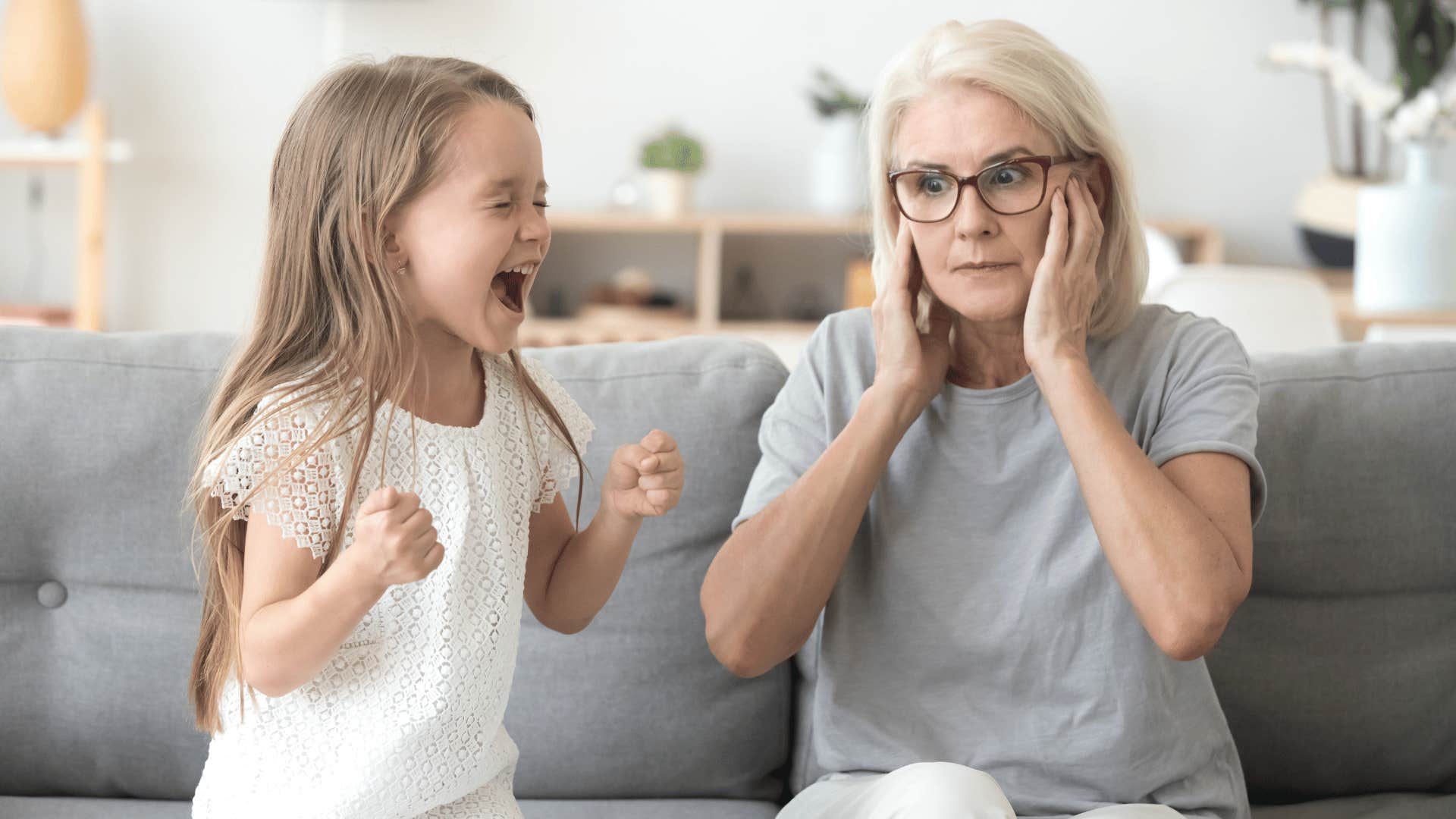Grandmother plugs ears around screaming child of her grown kid