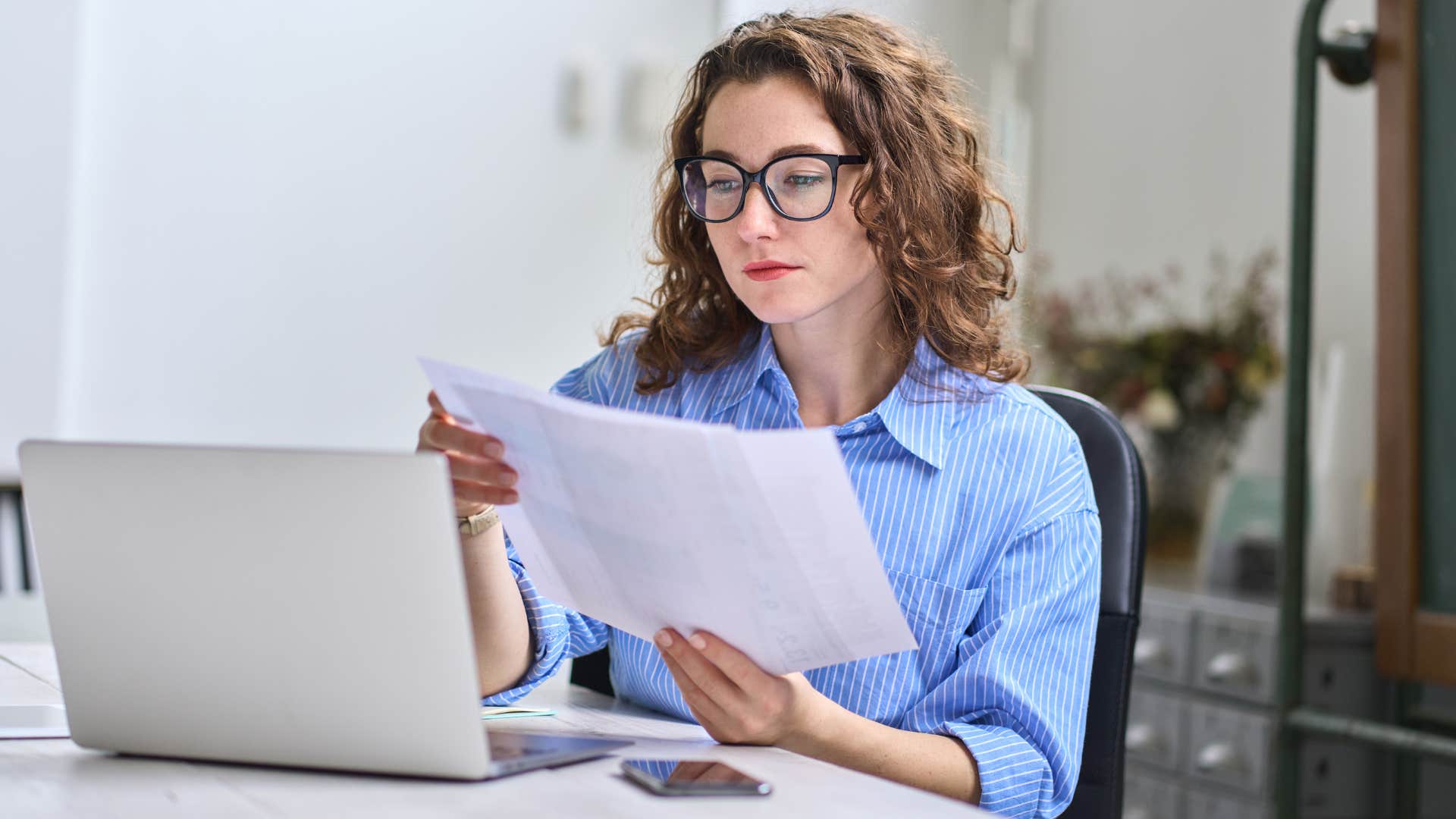 woman saying i'm just busy as woman in blue shirt looks through paper work while sitting down with glasses