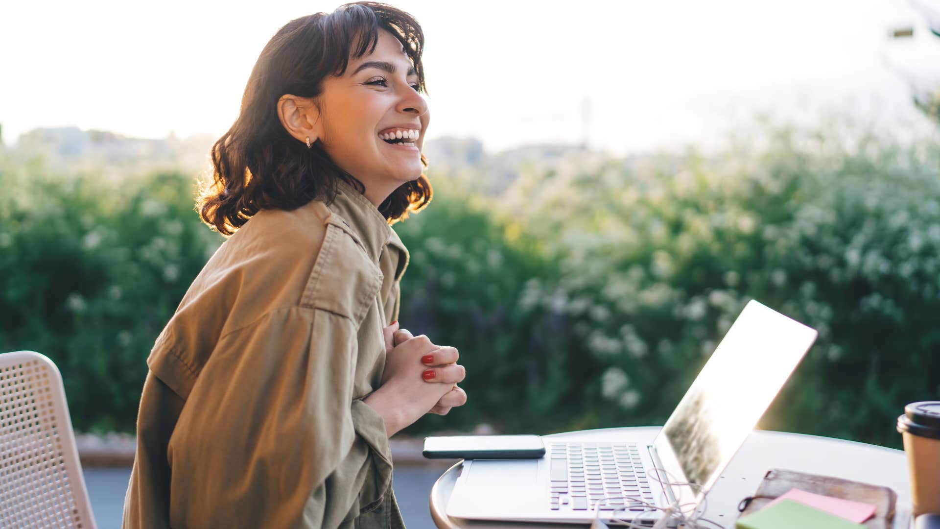 Woman who is an adult child of divorced parents works independently outdoors on her laptop