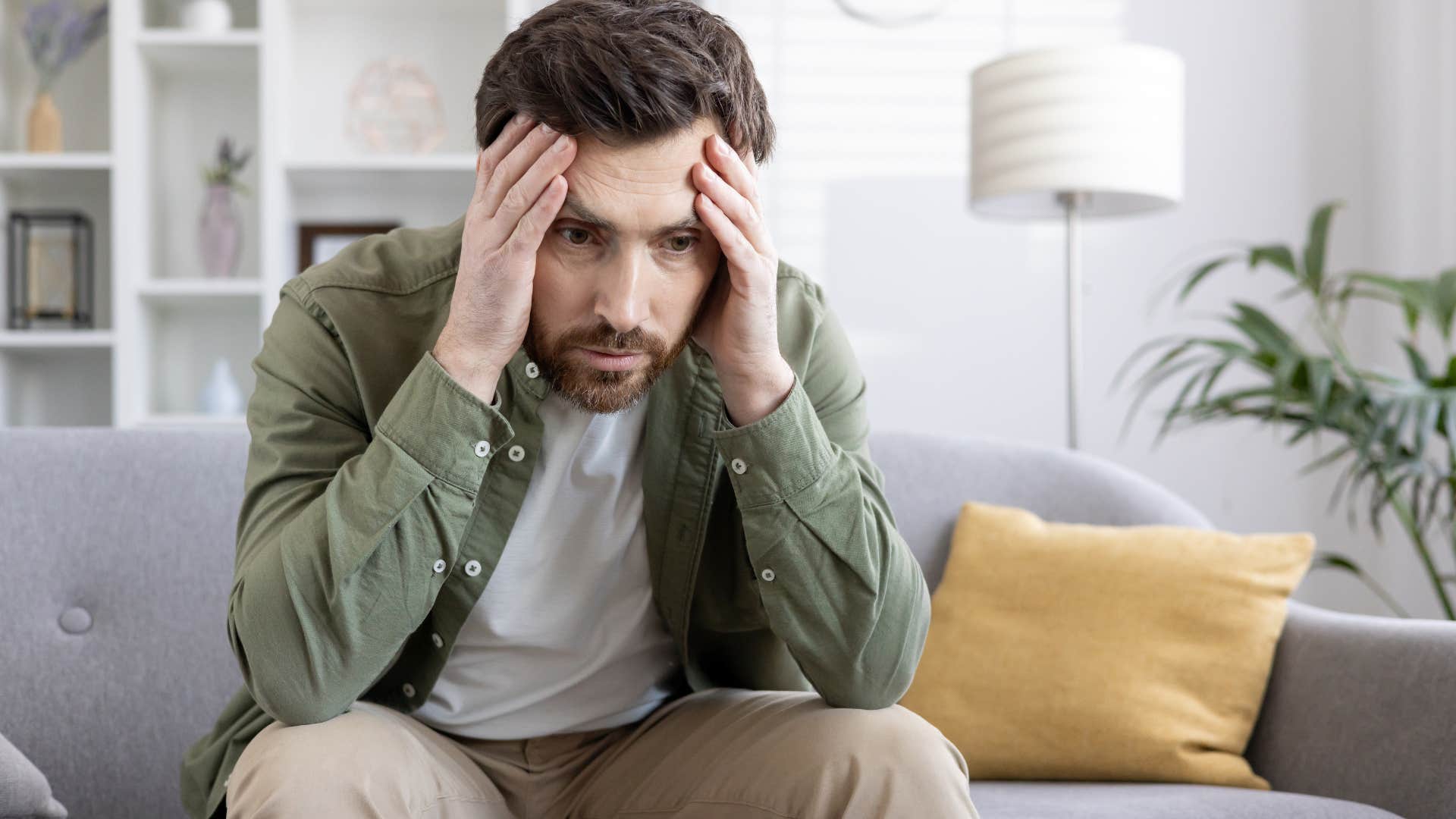 Man who is an adult child of divorce holding his head looking stressed
