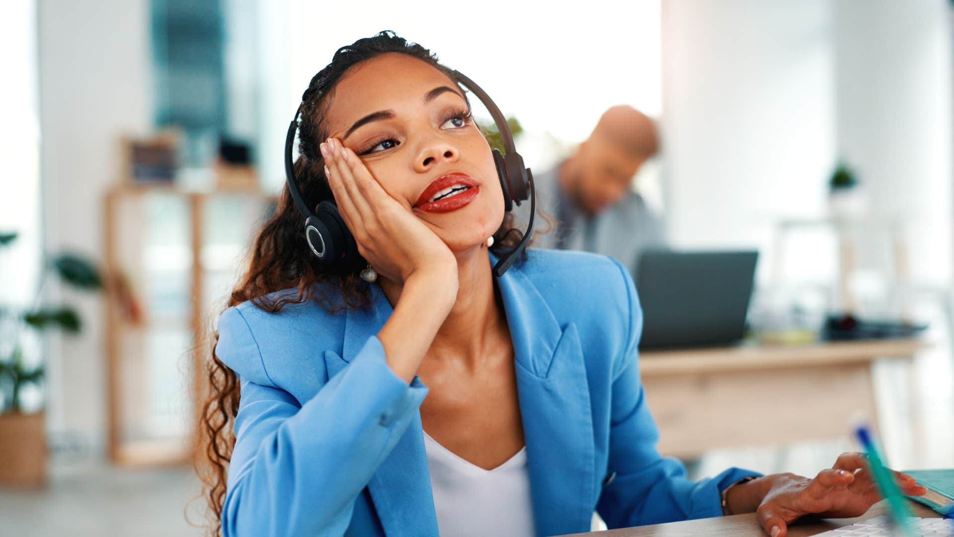 annoyed employee sitting at desk with headset on