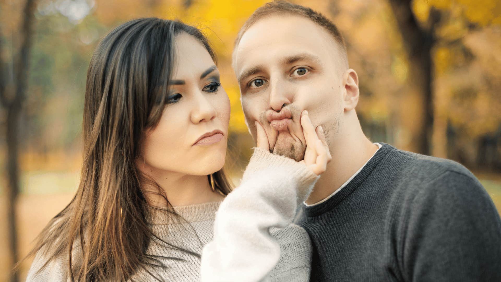 Man looking irritated when a woman he probably shouldn't marry squeezes his face